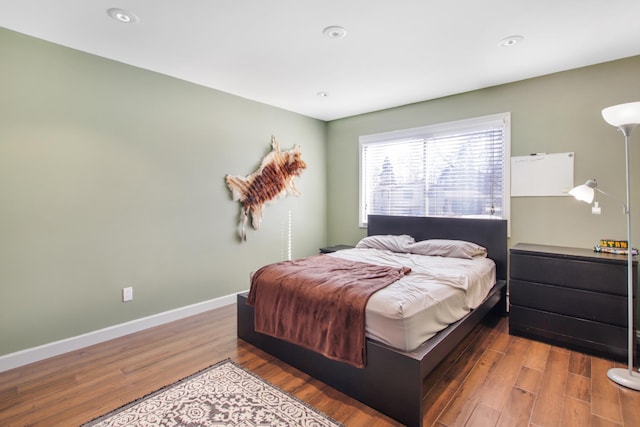 bedroom with recessed lighting, wood finished floors, and baseboards