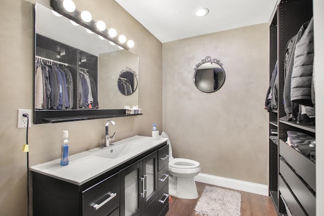 bathroom featuring toilet, vanity, baseboards, and wood finished floors