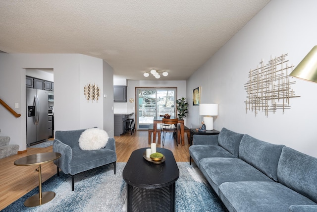 living area featuring stairs, a textured ceiling, and light wood-style flooring