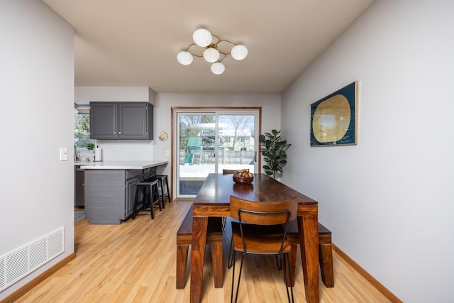 dining space featuring light wood-style floors, visible vents, baseboards, and an inviting chandelier