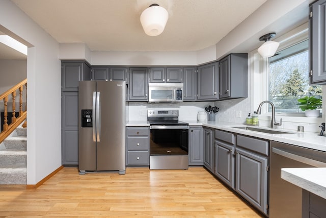 kitchen with decorative backsplash, appliances with stainless steel finishes, gray cabinets, and a sink