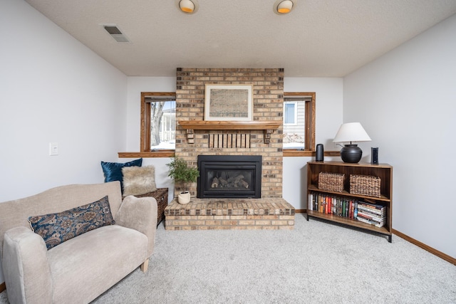 carpeted living room with visible vents, a fireplace, a textured ceiling, and baseboards