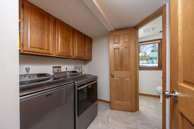 laundry area featuring a textured ceiling, washing machine and dryer, visible vents, baseboards, and cabinet space