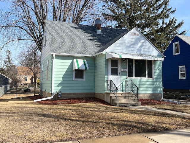 bungalow with fence, roof with shingles, and a chimney