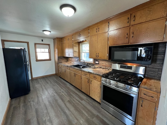 kitchen with wood finished floors, baseboards, a sink, decorative backsplash, and black appliances