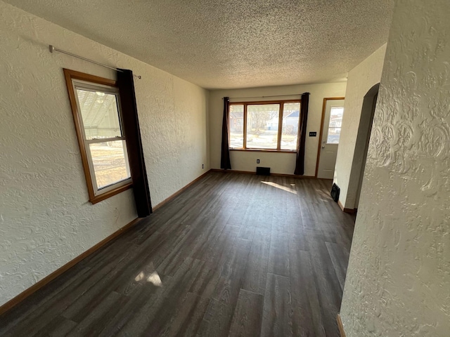 spare room with dark wood-style floors, a textured wall, baseboards, and a textured ceiling