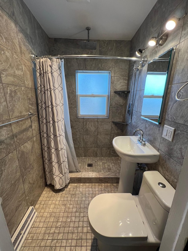 full bathroom with tiled shower, toilet, and tile walls