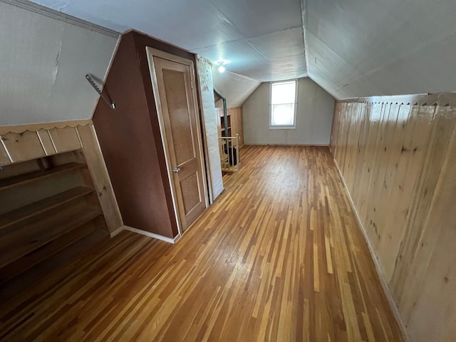 additional living space with hardwood / wood-style flooring, wood walls, and vaulted ceiling