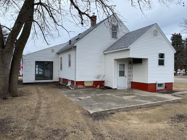 back of property featuring a patio area, a chimney, and roof with shingles