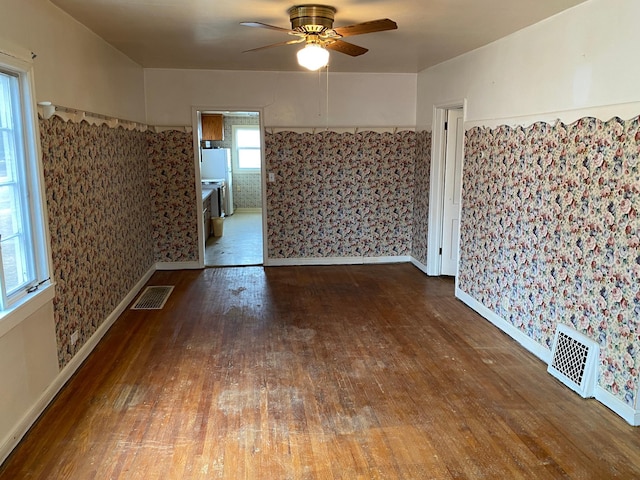 unfurnished room featuring baseboards, ceiling fan, visible vents, and hardwood / wood-style floors