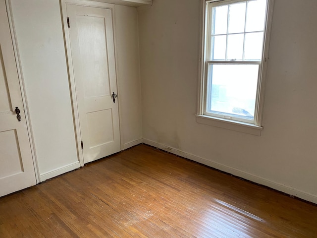 unfurnished bedroom featuring light wood-type flooring, multiple windows, and baseboards