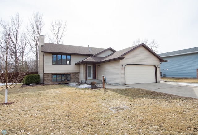 split level home with a front yard, driveway, a chimney, a garage, and brick siding