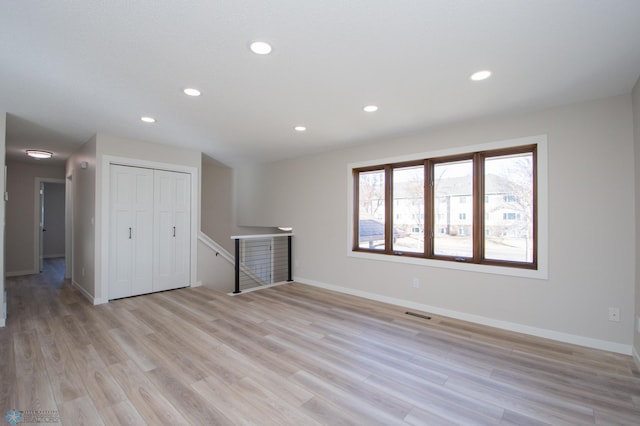 empty room with light wood finished floors, visible vents, recessed lighting, and baseboards