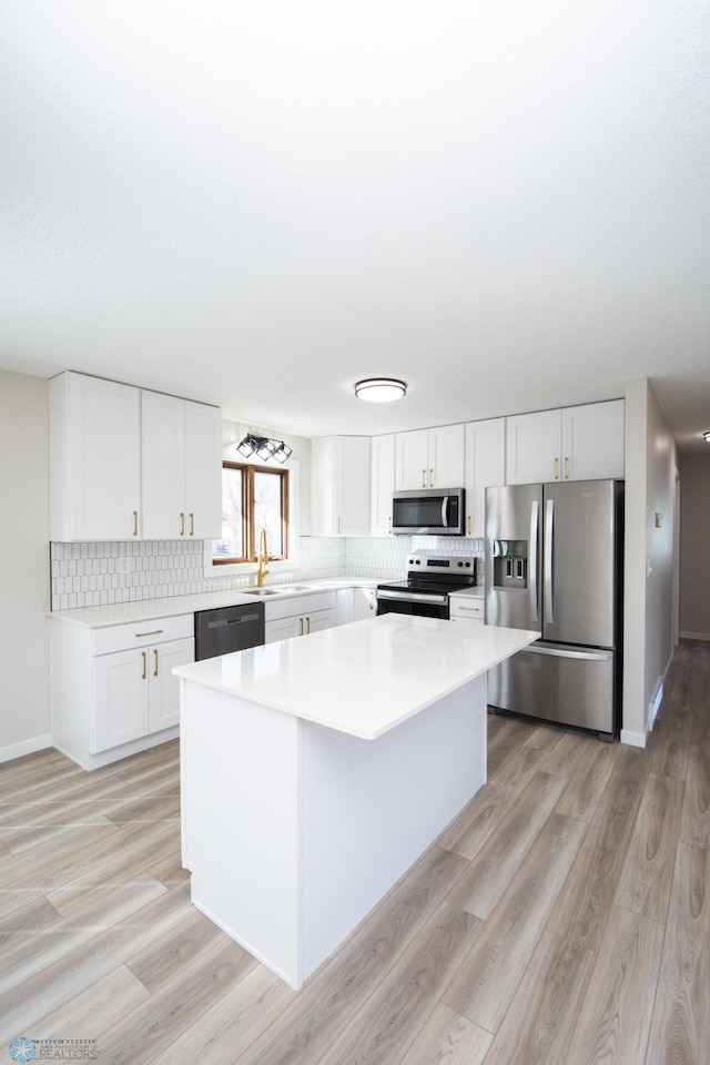 kitchen featuring backsplash, a kitchen island, light countertops, stainless steel appliances, and a sink