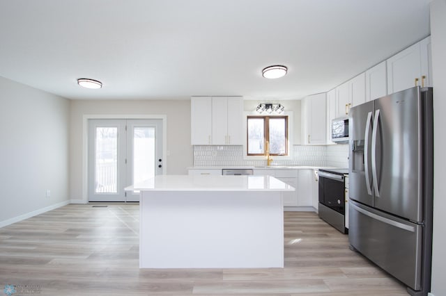 kitchen featuring stainless steel appliances, light countertops, white cabinetry, backsplash, and a center island