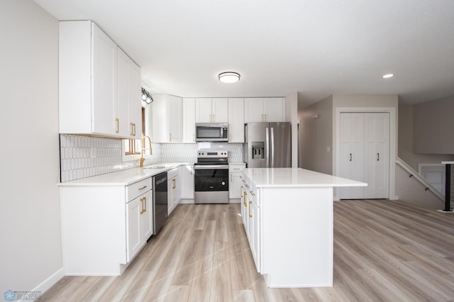 kitchen with a sink, stainless steel appliances, light countertops, backsplash, and a center island