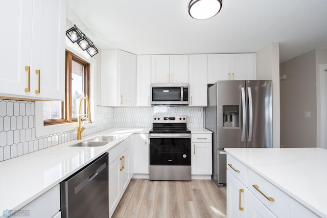 kitchen with light wood finished floors, light countertops, appliances with stainless steel finishes, white cabinetry, and a sink