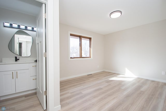 interior space featuring visible vents, baseboards, wood finished floors, and vanity