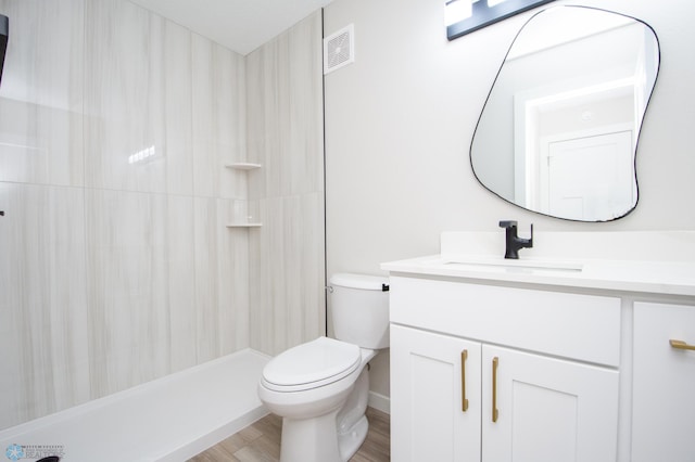 bathroom with vanity, wood finished floors, visible vents, a shower, and toilet