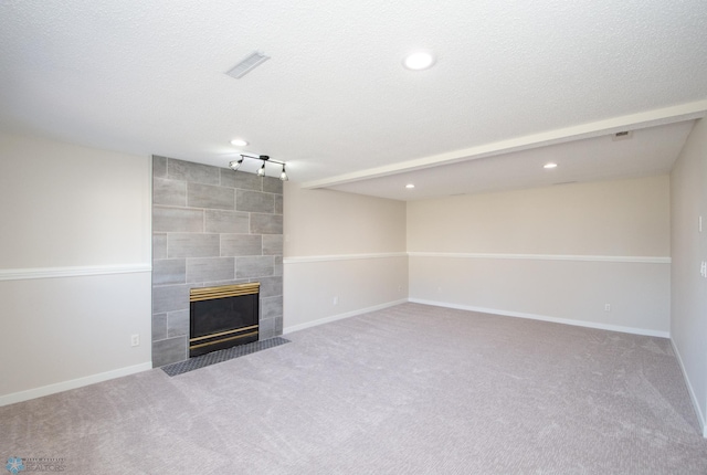 unfurnished living room with visible vents, carpet floors, baseboards, and a tiled fireplace