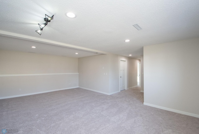 empty room with light carpet, recessed lighting, baseboards, and a textured ceiling