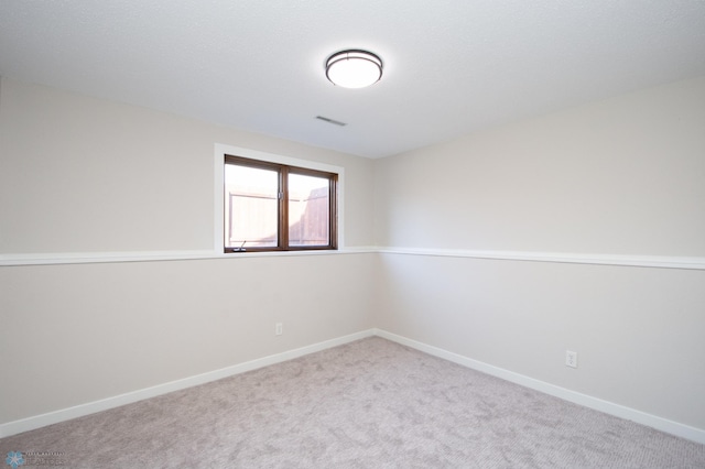 spare room featuring carpet, visible vents, and baseboards