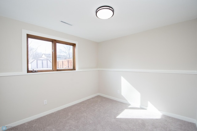 spare room with carpet flooring, baseboards, and visible vents