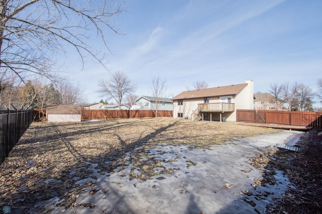 back of property with a shed, a wooden deck, a fenced backyard, a chimney, and an outdoor structure