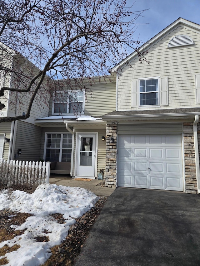 view of front of home featuring aphalt driveway, stone siding, and an attached garage