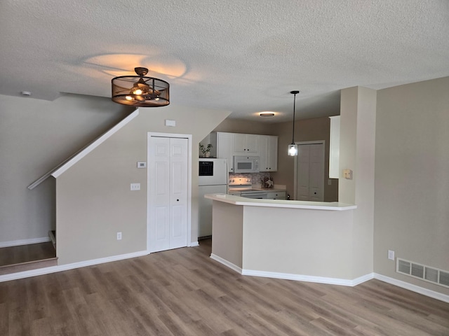 kitchen with visible vents, wood finished floors, white cabinetry, white appliances, and light countertops