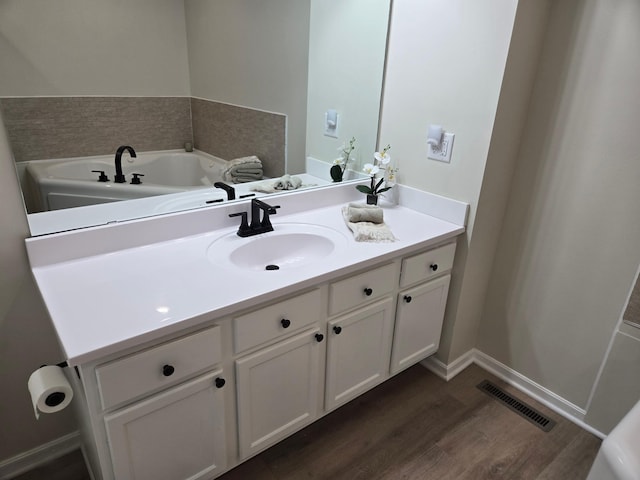 bathroom featuring visible vents, baseboards, wood finished floors, and vanity