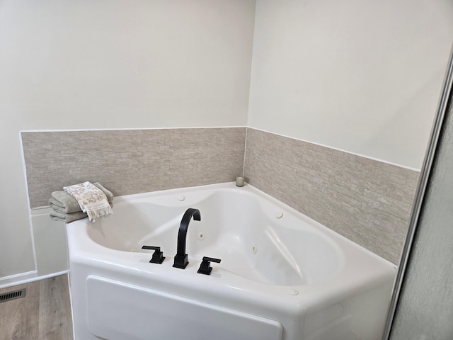 full bathroom with visible vents, wood finished floors, and a whirlpool tub