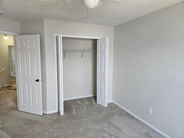 unfurnished bedroom featuring a closet, carpet flooring, a textured ceiling, and baseboards