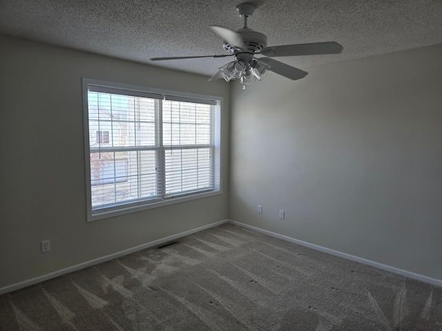 carpeted empty room with a ceiling fan, visible vents, baseboards, and a textured ceiling