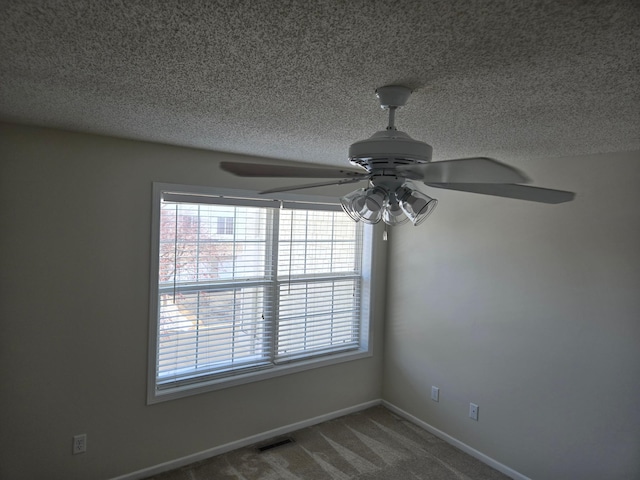 carpeted spare room featuring visible vents, a textured ceiling, and baseboards