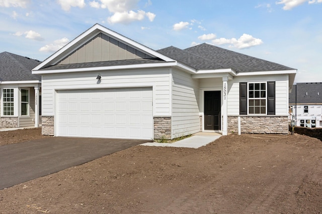 view of front of home with stone siding, aphalt driveway, board and batten siding, and an attached garage