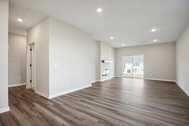 unfurnished living room with baseboards, dark wood finished floors, and recessed lighting