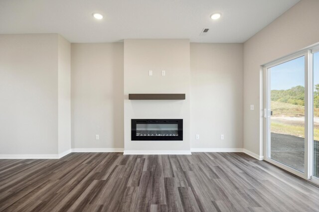 unfurnished living room with recessed lighting, wood finished floors, visible vents, baseboards, and a glass covered fireplace