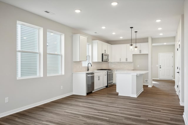 kitchen with stainless steel appliances, backsplash, a sink, and white cabinetry