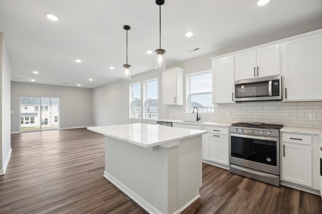 kitchen with a kitchen island, a sink, appliances with stainless steel finishes, backsplash, and dark wood finished floors