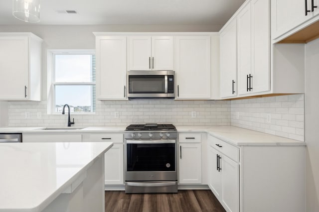 kitchen with stainless steel appliances, dark wood-style flooring, white cabinets, and a sink