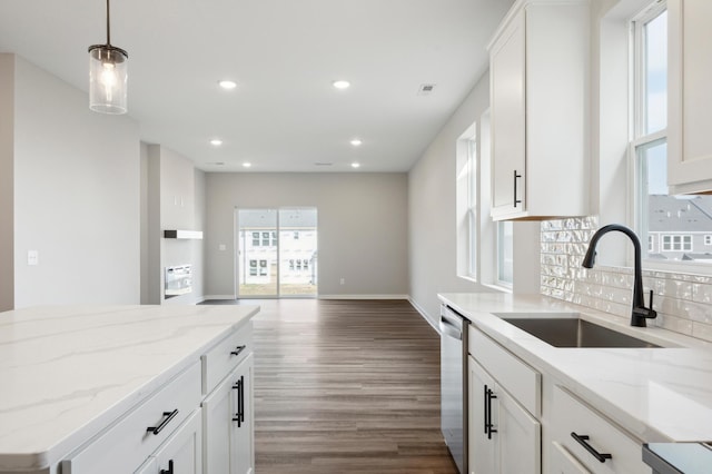 kitchen with recessed lighting, stainless steel dishwasher, dark wood-type flooring, a sink, and light stone countertops