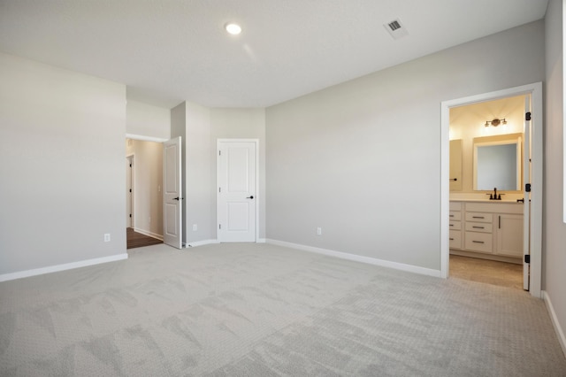 unfurnished bedroom with light carpet, baseboards, visible vents, and a sink