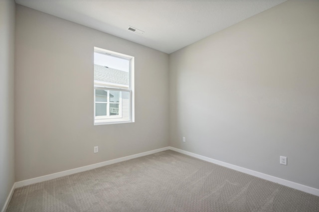 empty room featuring carpet, visible vents, and baseboards