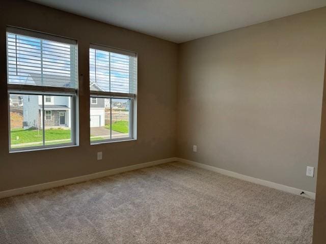 spare room with baseboards and carpet flooring