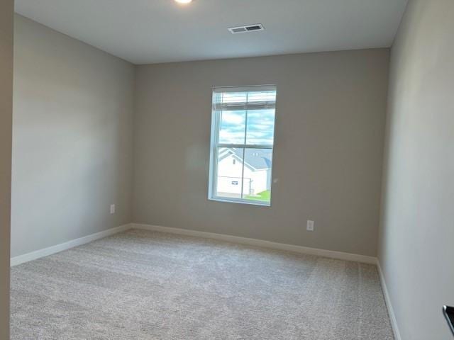 empty room with carpet, visible vents, and baseboards