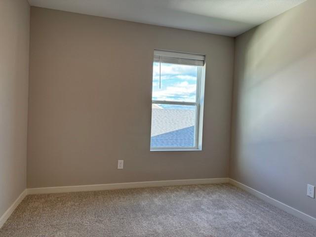 carpeted empty room featuring baseboards