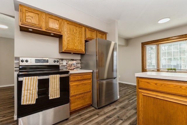 kitchen featuring dark wood-style flooring, baseboards, light countertops, appliances with stainless steel finishes, and brown cabinetry