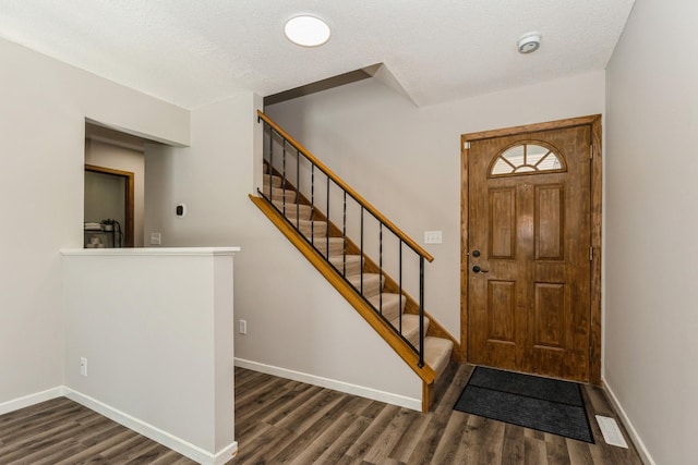 entrance foyer featuring a textured ceiling, dark wood-type flooring, and baseboards