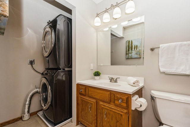 bathroom with toilet, vanity, stacked washer and clothes dryer, and tile patterned floors